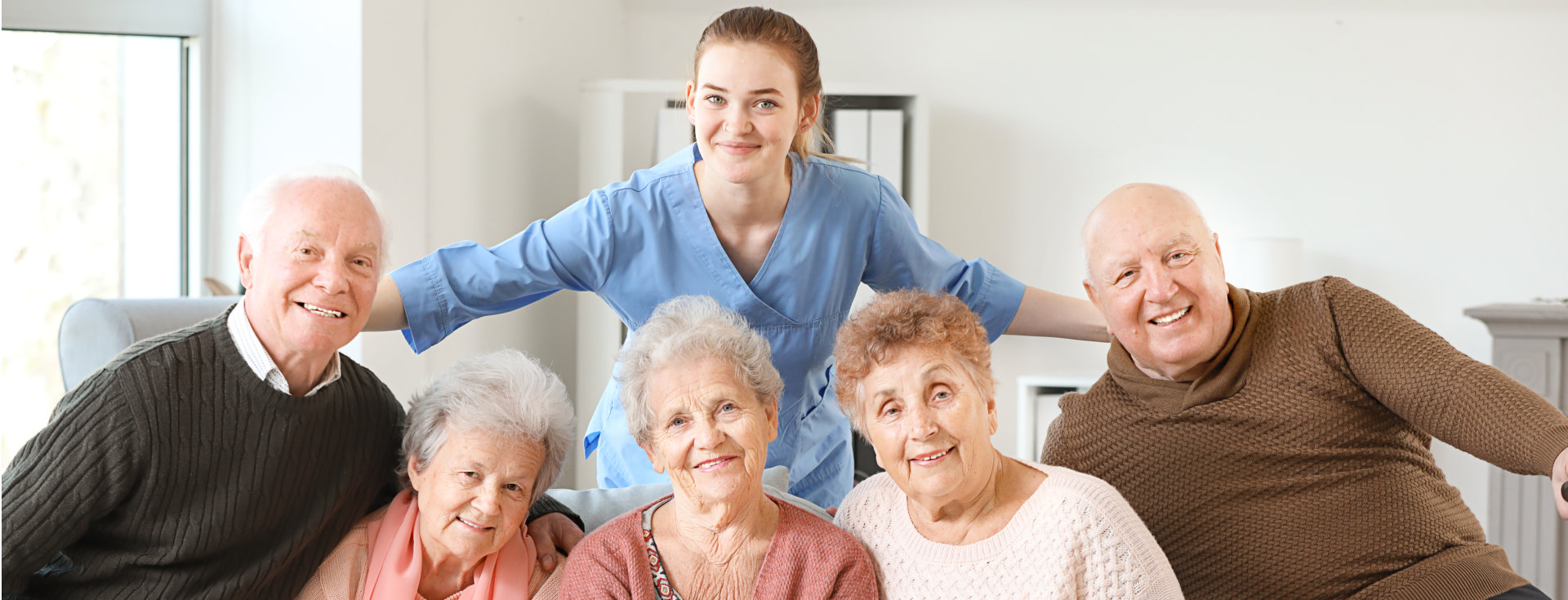 a caregiver and a group of elderly person smiling