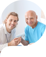 a caregiver and an elderly man both smiling