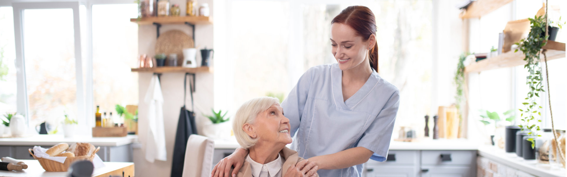 a caregiver and an elderly woman staring each other and both smiling