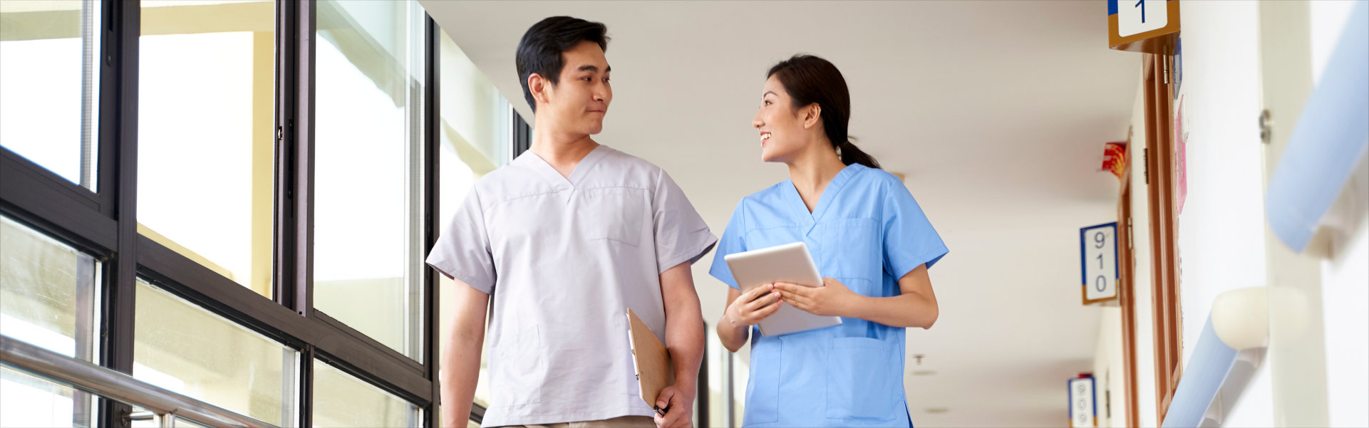 happy young asian physical therapists walking talking in hallway of nursing home