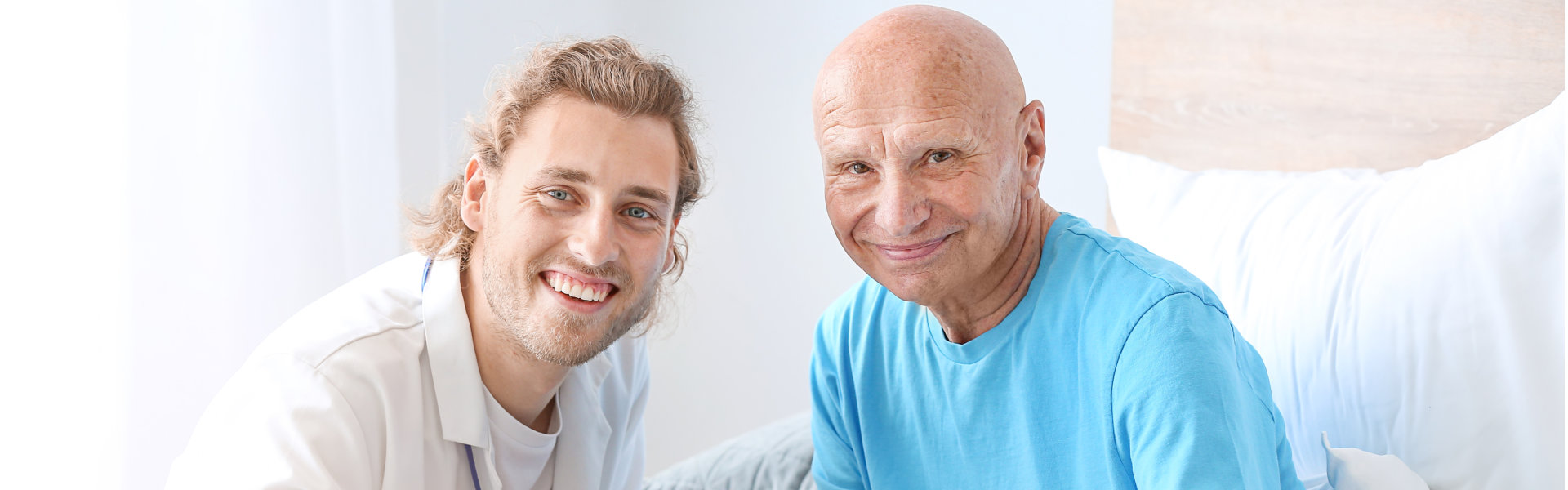 a caregiver and an elderly man both smiling